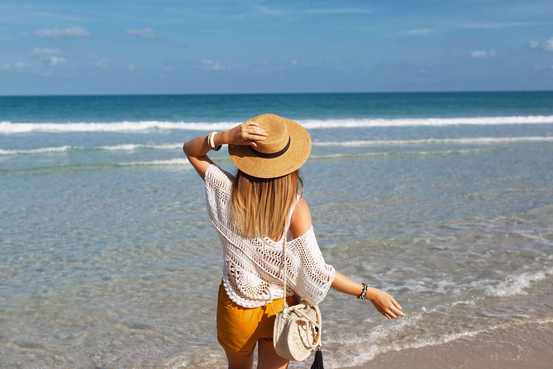 woman-holding-straw-bag-walking-beach (1).jpg